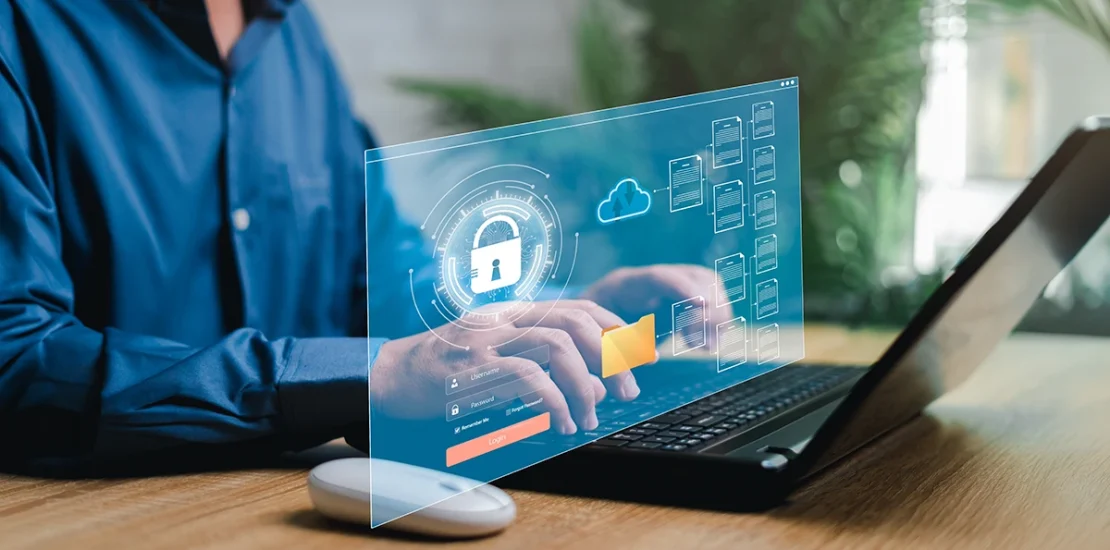 A professional using a laptop with a digital cybersecurity interface overlay, illustrating NESA Compliance UAE 2026 and how national cybersecurity regulations protect business data through cloud security and encrypted file management.