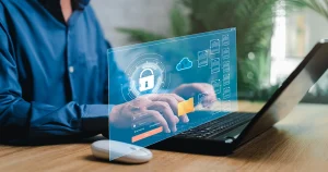 A professional using a laptop with a digital cybersecurity interface overlay, illustrating NESA Compliance UAE 2026 and how national cybersecurity regulations protect business data through cloud security and encrypted file management.