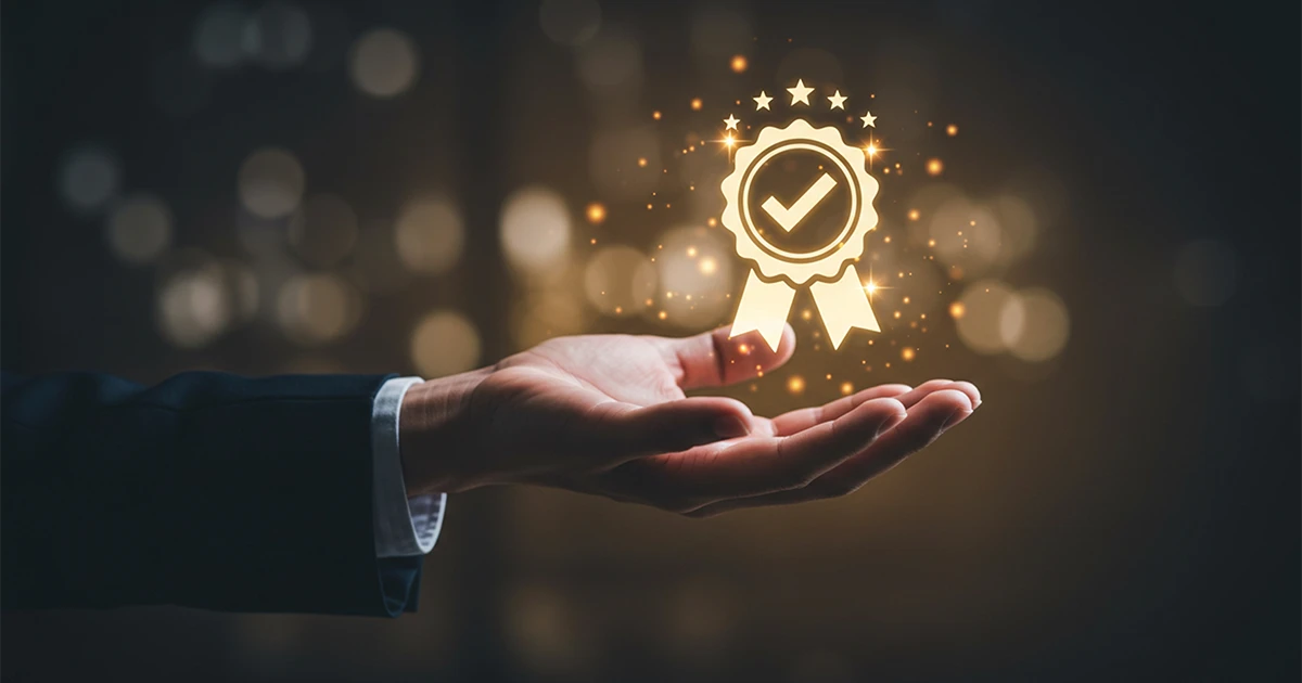 A professional's hand held out toward a glowing golden seal icon with a checkmark and stars, symbolizing the prestige of the Business Excellence Awards in UAE and a commitment to high corporate standards.