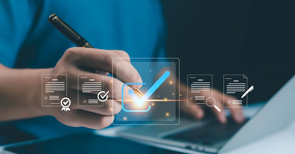 Close-up of a businessman in the UAE using a digital pen to check off compliance requirements on a laptop screen, illustrating the final audit and certification stages of an ISO 27001 implementation timeline.