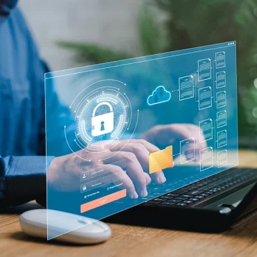 A professional using a laptop with a digital cybersecurity interface overlay, illustrating NESA Compliance UAE 2026 and how national cybersecurity regulations protect business data through cloud security and encrypted file management.